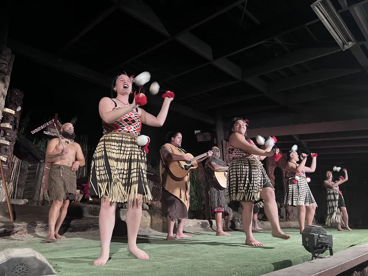 Um artista Māori em traje tradicional a girar poi durante uma atuação cultural.
